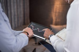 Two digital asset consulting experts analyzing financial charts on a tablet with notes.